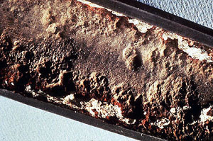 Figure 14-6. Typical gouging caused by caustic attack developed under an original adherent deposit. Note irregular depressions and white (Na2CO3) deposits remaining around edges of original deposit area.